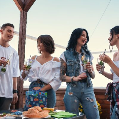 It's my birthday. Cheerful young people chatting and drinking cocktails at a rooftop party